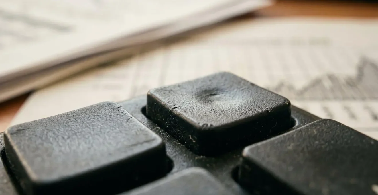 Calculatrice entourée de documents financiers symbolisant les frais cachés