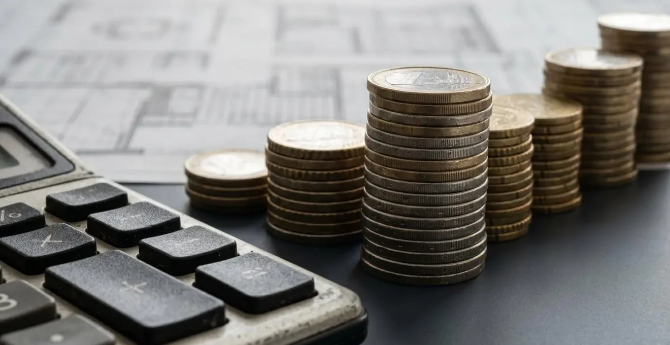 Visualisation de l'effet de levier avec des piles de pièces de monnaie de différentes hauteurs à côté d'une calculatrice.