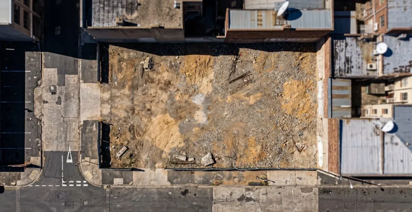Vue en plongée d'une parcelle constructible entourée de bâtiments existants en zone urbaine dense