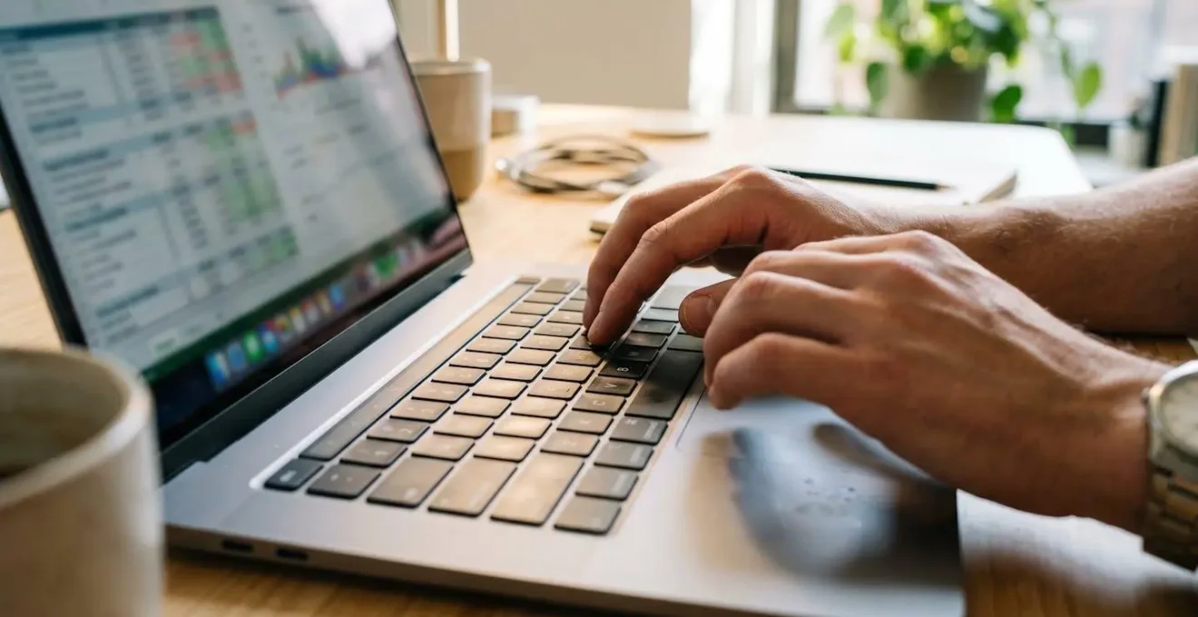 Gros plan sur des mains tapant sur un clavier d'ordinateur portable moderne avec un graphique financier totalement flouté à l'écran