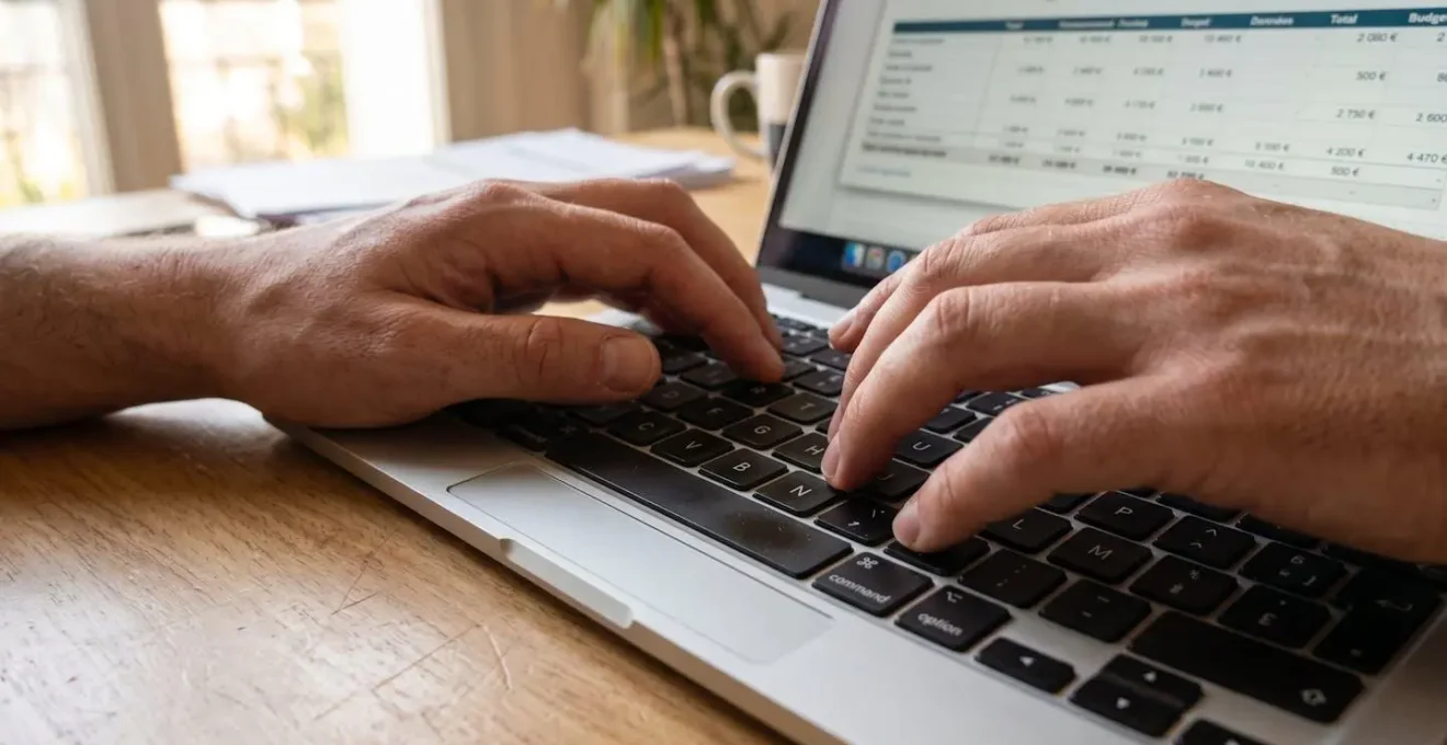 Gros plan sur des mains tapant sur un clavier d'ordinateur portable moderne avec un graphique financier totalement flouté à l'écran